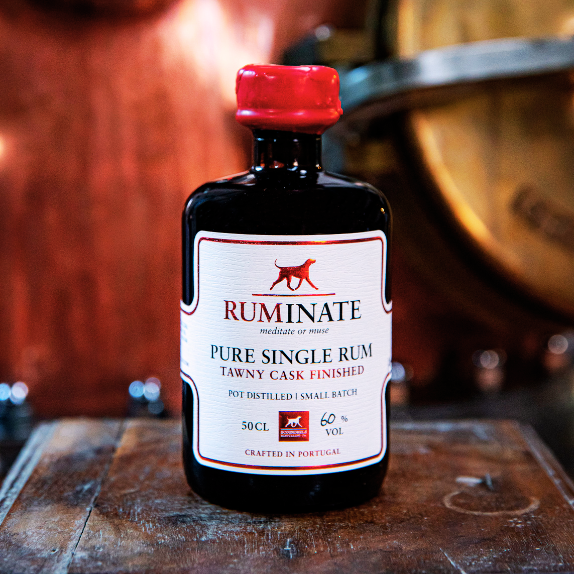 Bottle of Ruminate Pure Single Rum in front of a wooden cask